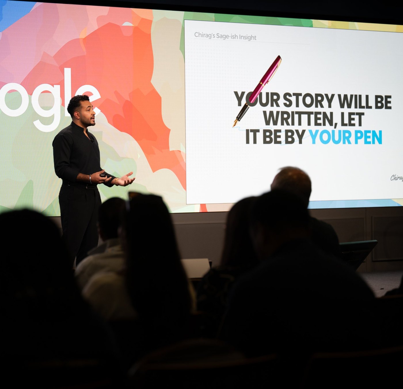 Chirag Speaks on stage, mid-story, with his closing slide behind him and a full room in front